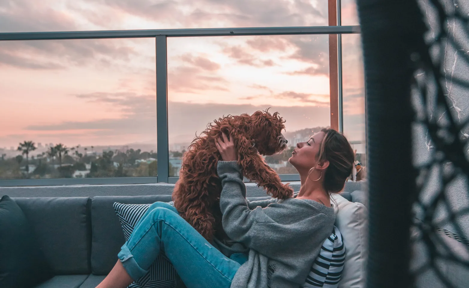 woman holding dog on a balcony couch